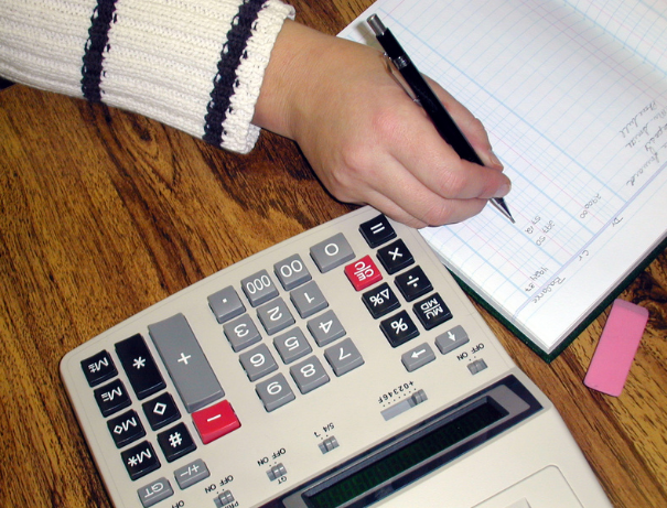 a man is doing accounts, a calculator is place beside the book